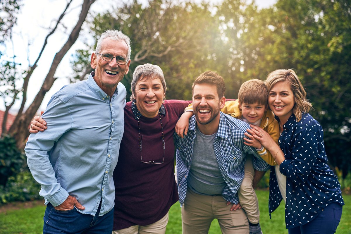 Three generations of a family smiling together outdoors